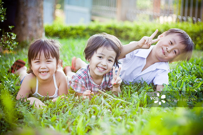 三个孩子在草地上欢笑图片素材