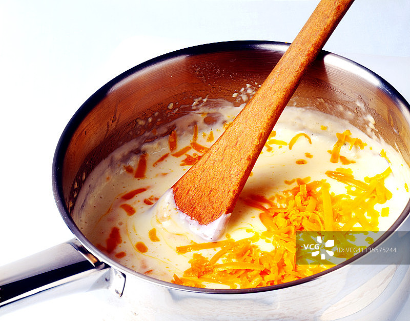 制作奶酪酱：将磨碎的奶酪加入平底锅图片素材
