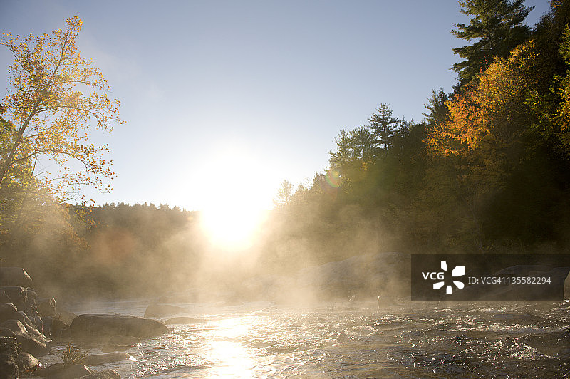美国马萨诸塞州谢尔本瀑布，阳光明媚的秋日，阳光洒在山脊上，雾气笼罩着鹿田河图片素材