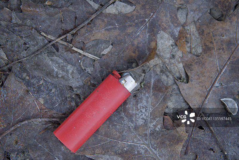 丢弃在腐烂树叶上的打火机图片素材