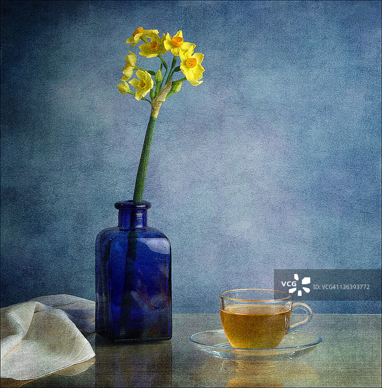 蓝色瓶子里的纳吉斯花和一杯茶图片素材