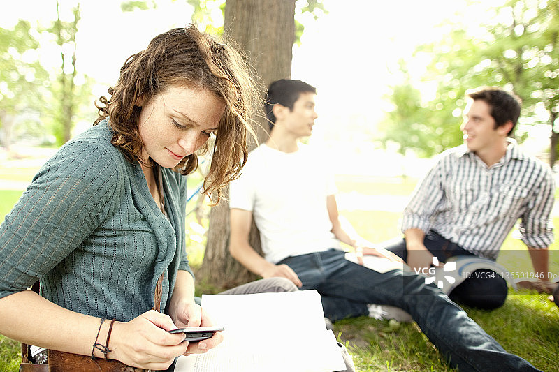 在草地上使用手机的学生图片素材