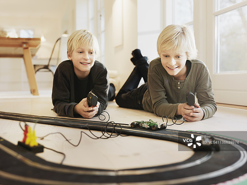 男孩们在地板上玩赛道玩具图片素材