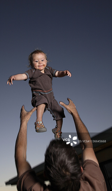 父亲将女儿抛向傍晚的天空图片素材