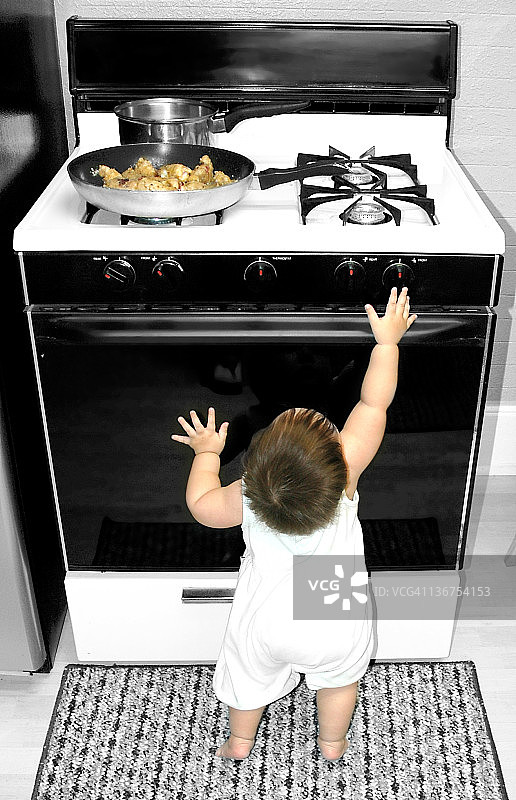婴儿伸手触摸炉灶图片素材