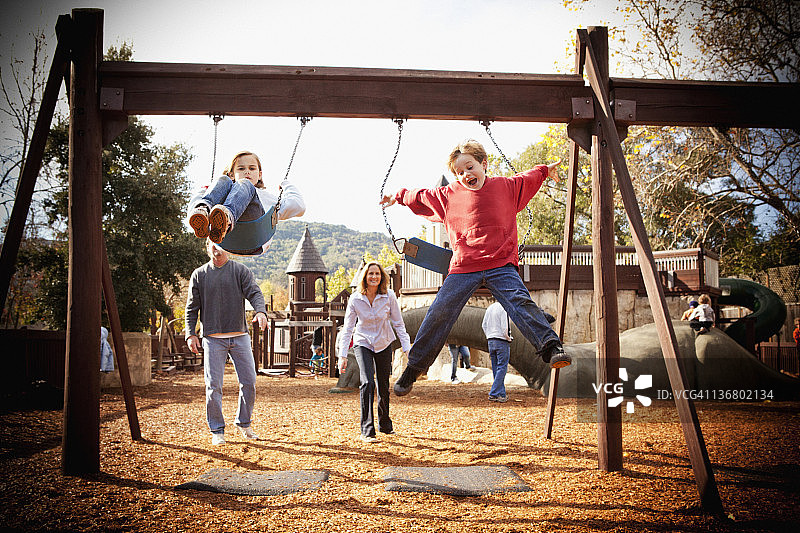 父母看着孩子荡秋千图片素材