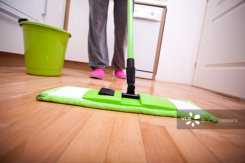 木地板上的绿色尘推和水桶图片素材
