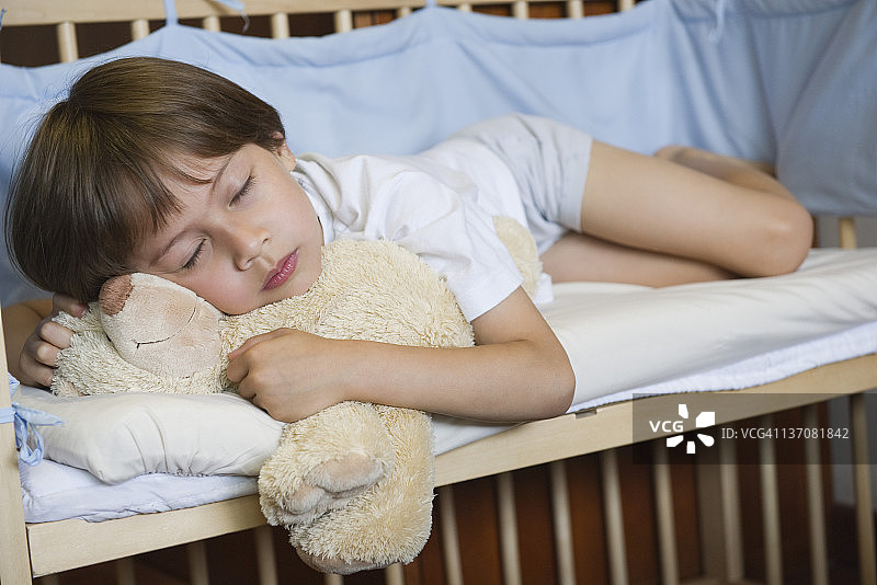 男孩睡在婴儿床里图片素材