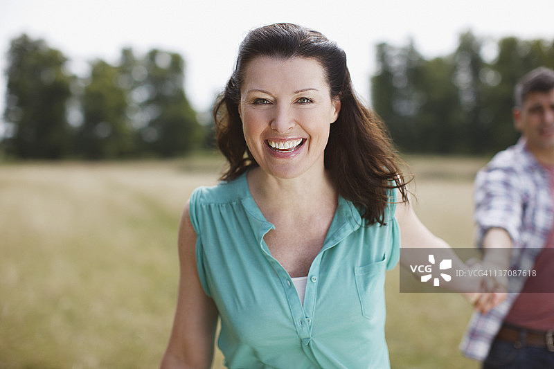 在乡间田野上手牵手的微笑情侣肖像图片素材