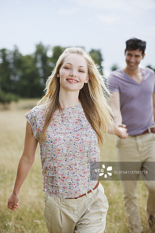 年轻情侣在乡村田野中手牵手的肖像图片素材