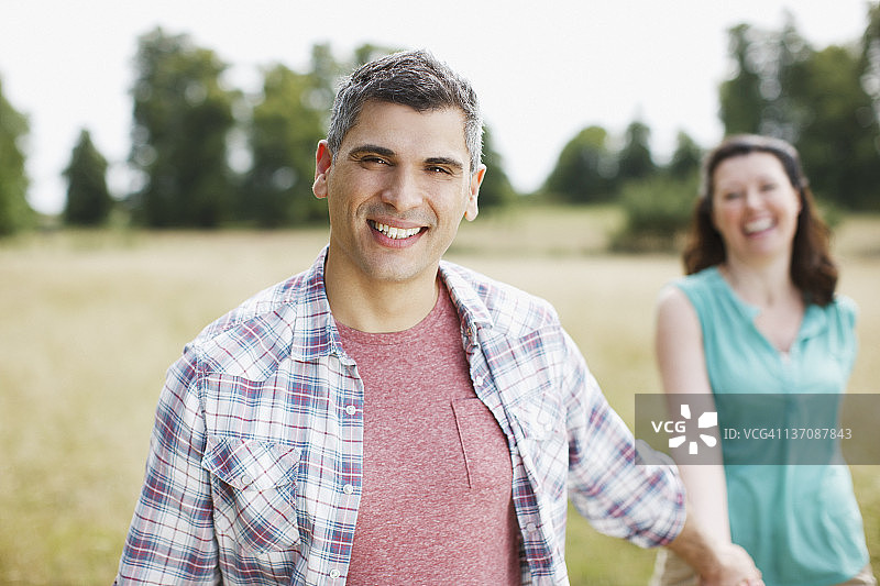 在乡间田野上手牵手的微笑情侣肖像图片素材