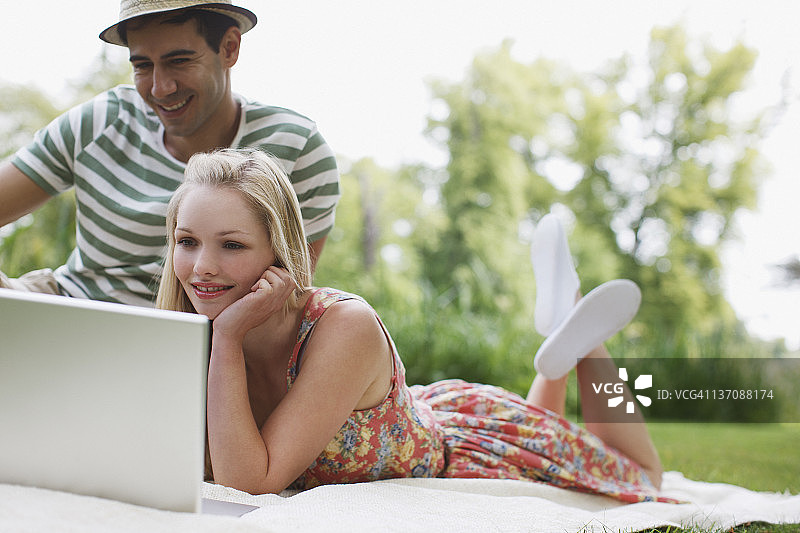 年轻夫妇在公园使用笔记本电脑图片素材