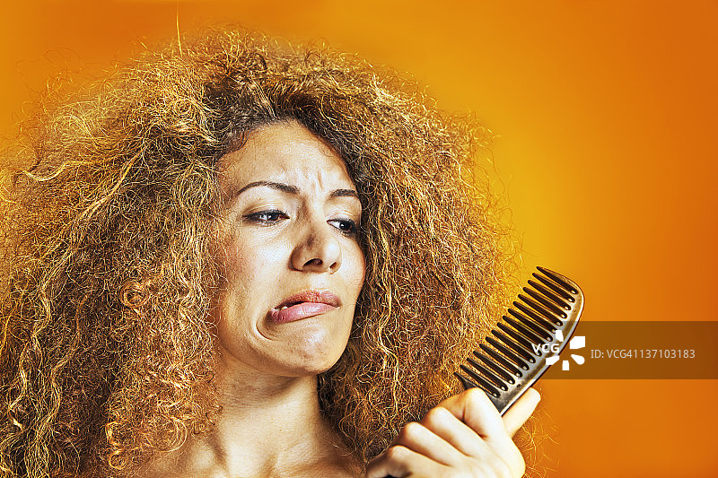 看着梳子的卷发女人图片素材