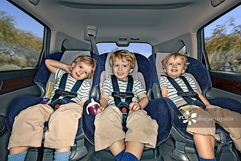 坐在汽车后座的三胞胎男孩图片素材