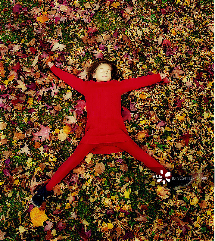 女孩躺在满是秋叶的草地上图片素材