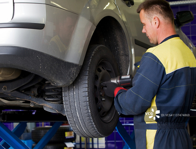 汽车修理店：汽车修理工更换轮胎图片素材