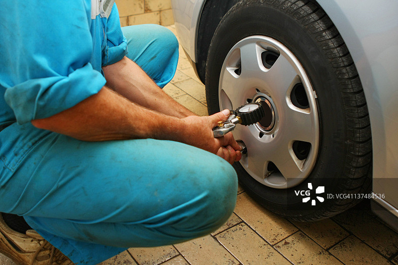 汽车维修店：汽车修理工更换轮胎图片素材