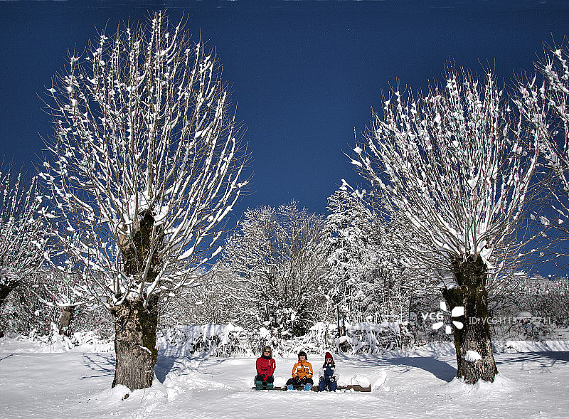 坐在雪地长椅上的女人和孩子们图片素材