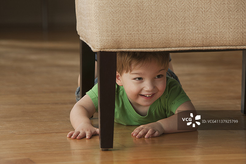 小男孩躲在椅子下面图片素材