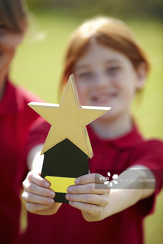 女孩在户外欢呼雀跃，手捧奖杯图片素材