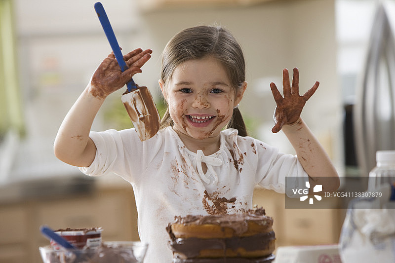 混血女孩给蛋糕上霜，弄得一团糟图片素材