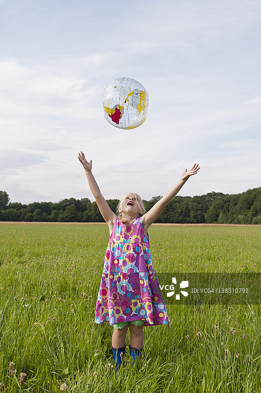 德国北莱茵-威斯特法伦州亨内夫的女孩在草地上扔沙滩球图片素材