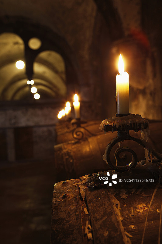 烛光照亮的酒窖中的酒桶图片素材