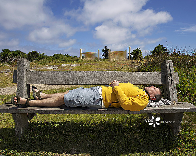 男子在海滩长椅上睡觉图片素材