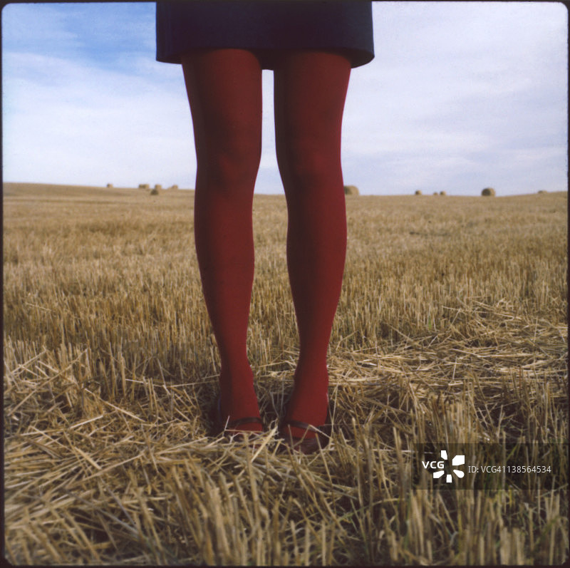 穿着红色紧身裤的女人站在麦茬地里图片素材