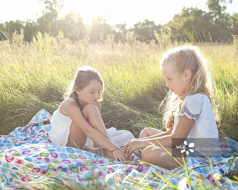 两个女孩坐在草地上制作草饰品图片素材
