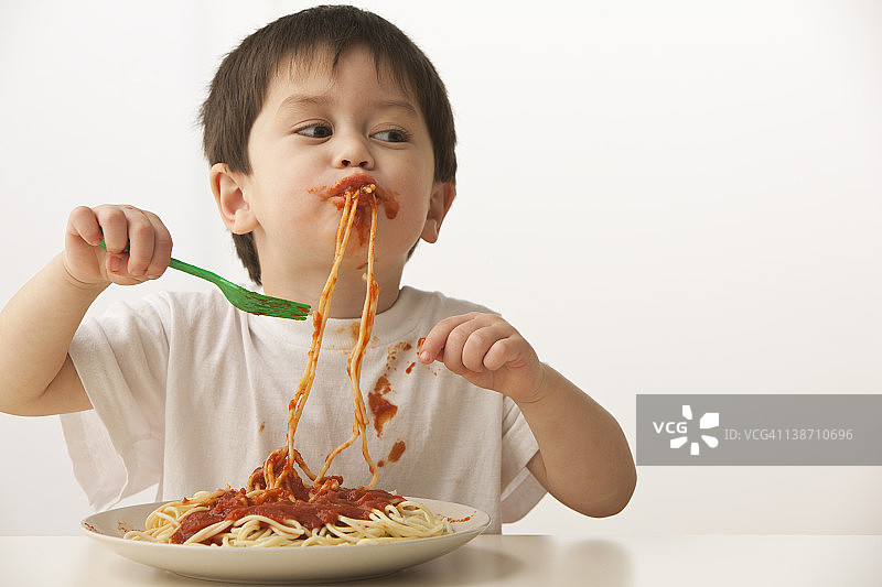 吃意大利面的混血男孩图片素材