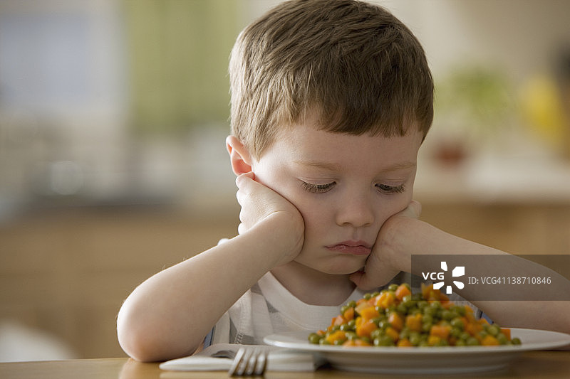 不高兴的白人男孩看着晚餐图片素材