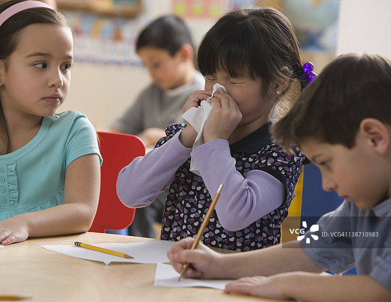 混血女孩在教室里擤鼻涕图片素材
