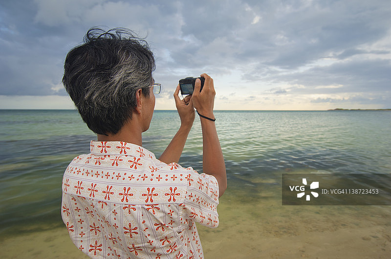 亚洲男人正在拍摄海洋照片图片素材