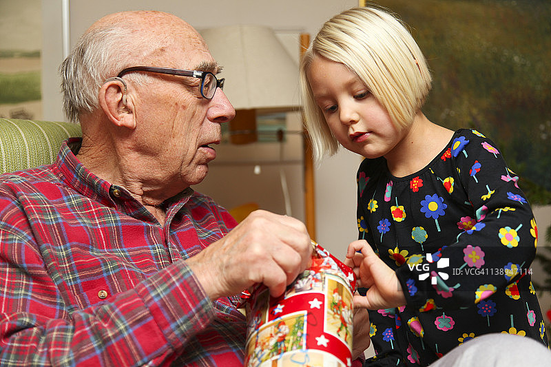 年轻女孩帮助爷爷打开圣诞礼物图片素材