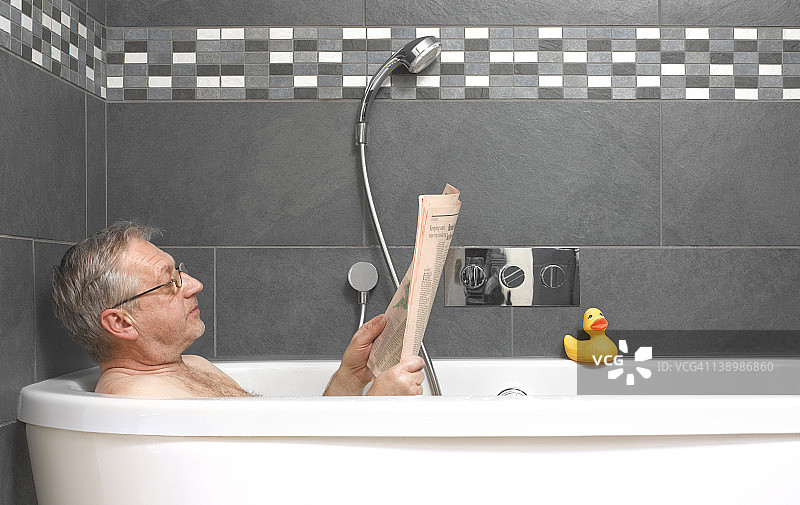 中年男人在浴缸里阅读财经报纸图片素材