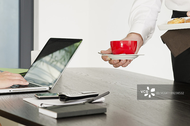 为办公桌前的女士提供的咖啡和糕点图片素材