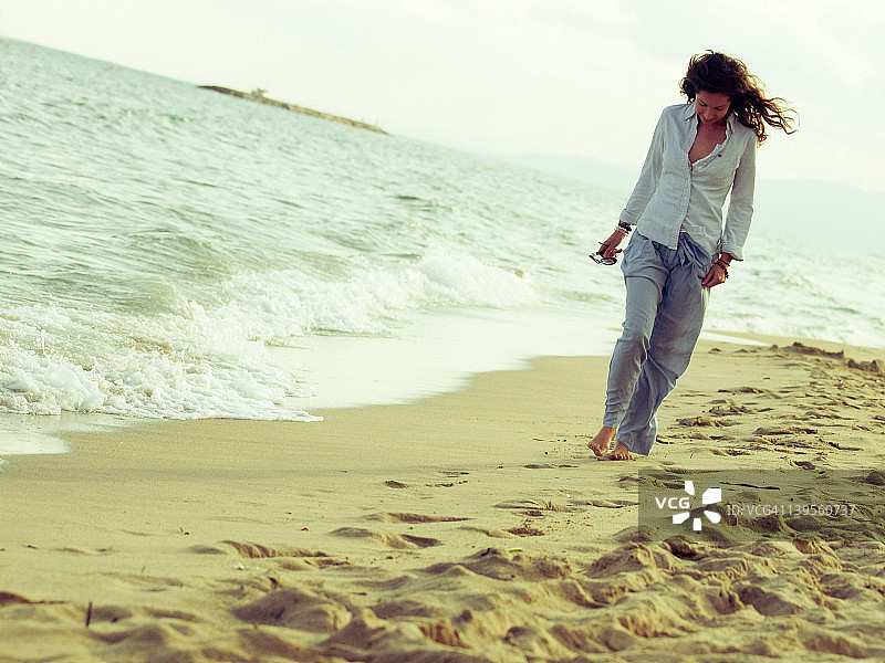 走在海滩岸边的年轻女人图片素材