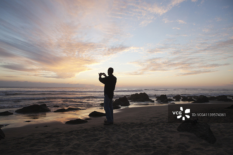 在海滩上拍摄地平线的男人图片素材