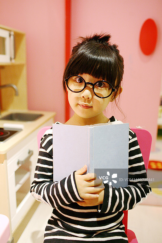 戴着眼镜拿着书的小女孩图片素材