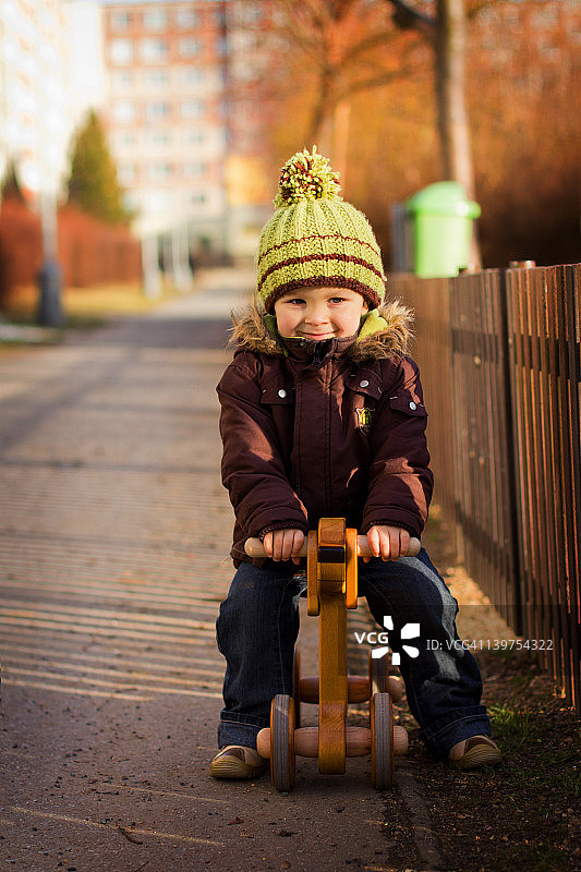 戴着帽子骑在木制狗上的男孩图片素材