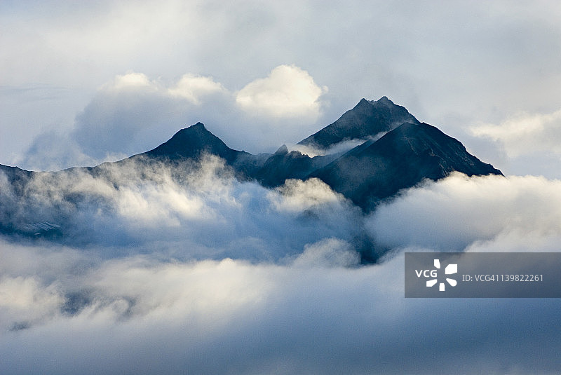 从阿拉斯加兰格尔-圣伊莱亚斯国家公园的风暴云中显现的山峰图片素材