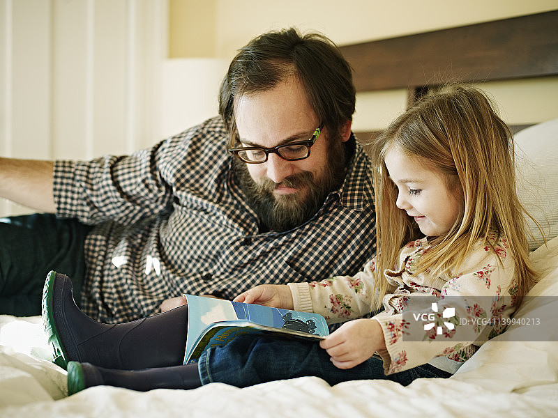 父女在床上阅读书籍图片素材