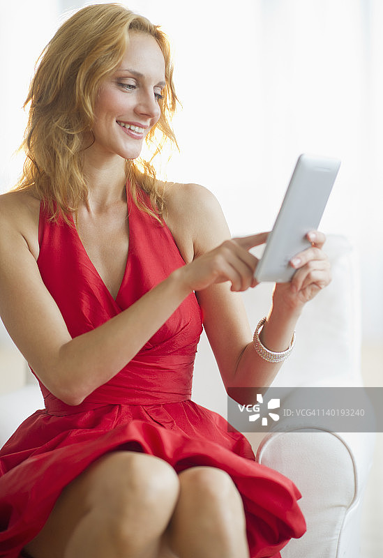 身穿红裙的女人使用平板电脑，影棚拍摄图片素材