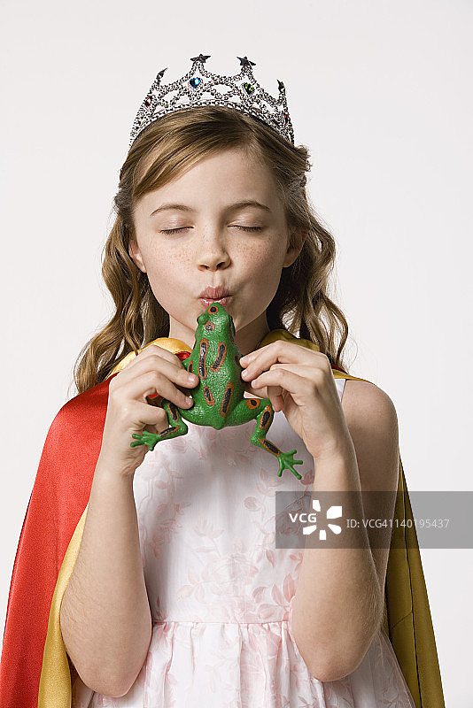影棚肖像8-9岁女孩穿公主裙亲吻玩具青蛙图片素材