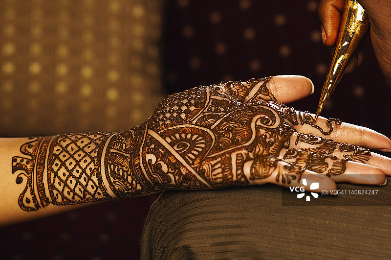 女士在婚礼新娘手掌上涂抹海娜图片素材