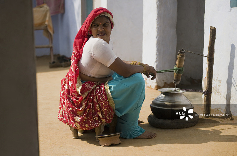 女人在印度哈里亚纳邦古尔冈的Farrukh Nagar搅拌黄油图片素材