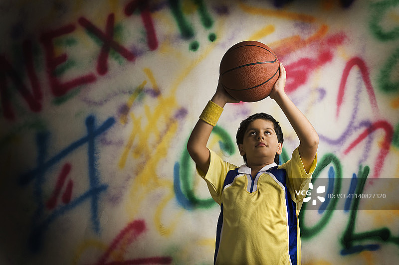 男孩在涂鸦墙前玩篮球图片素材