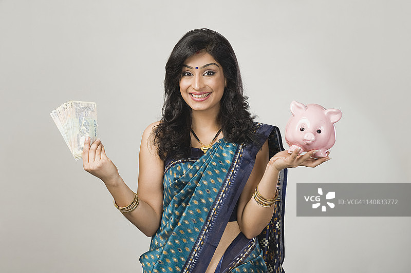 拿着钱和存钱罐的女性肖像图片素材