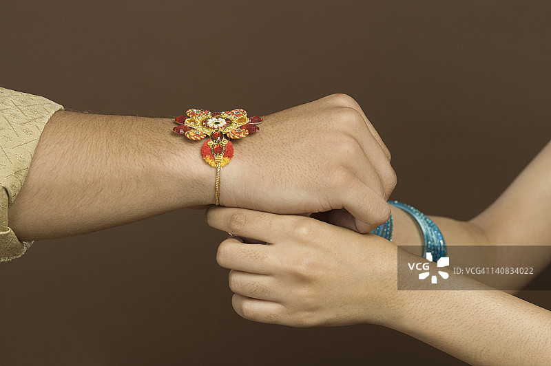 女人在哥哥手腕上系保护绳图片素材